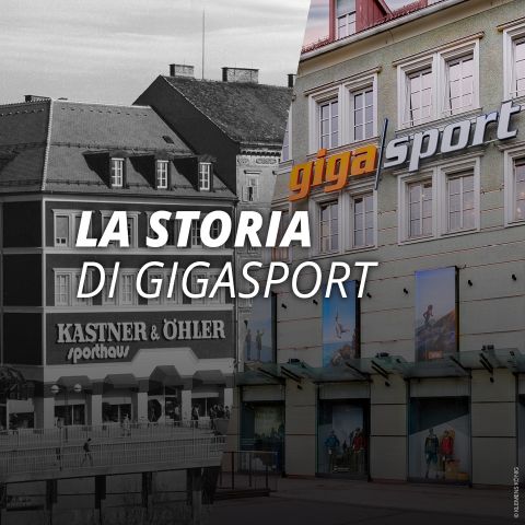 Un edificio con le insegne Gigasport e Kastner & Öhler, con grandi finestre e persone che passeggiano all'esterno. Il testo recita: "La storia di Gigasport.