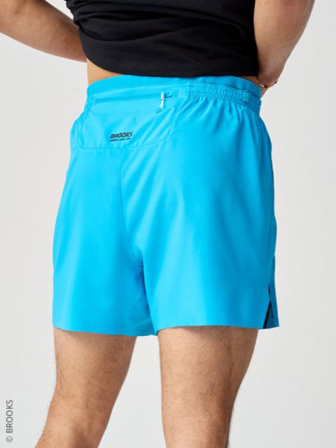 Persona in pantaloni sportivi azzurro chiaro e top nero, fotografata da dietro su sfondo chiaro.