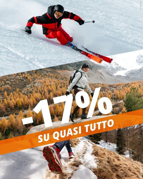 Uno sciatore che scende un pendio innevato, mentre sopra di lui un escursionista